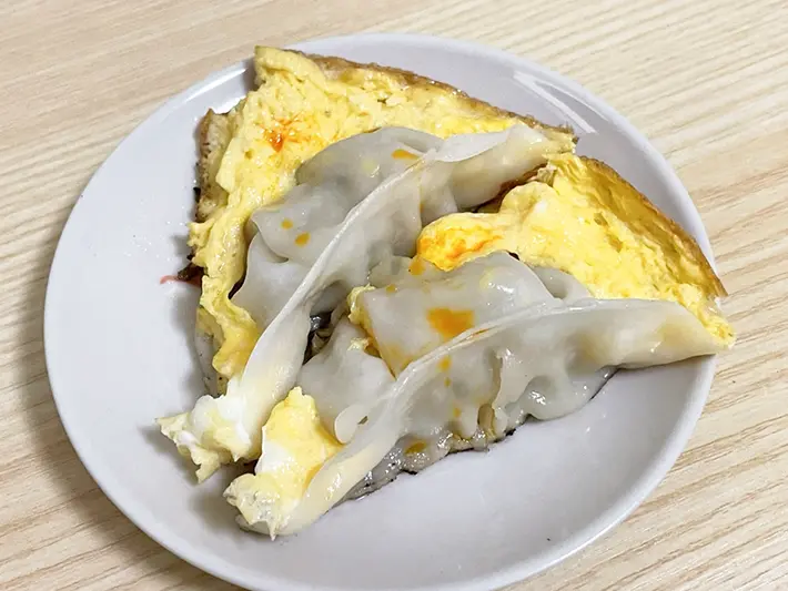 卵で羽を作った餃子にラー油をかける写真（撮影：grapeフード編集部）