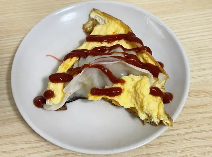 卵で羽を作った餃子にケチャップをかける写真（撮影：grapeフード編集部）
