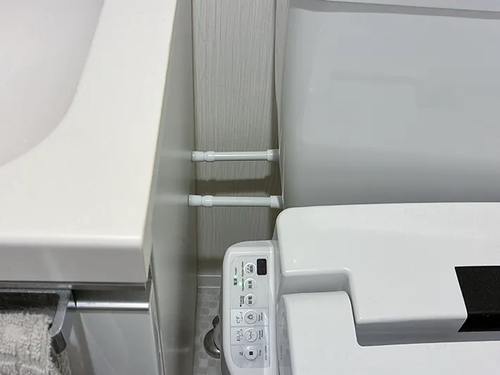 トイレのタンクと洗面台の間に設置した2本の短いつっぱり棒（撮影：grapeライフハック編集部）