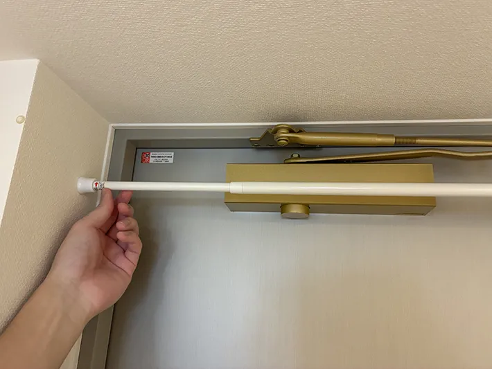 玄関ドアの上部につっぱり棒を設置する場面（撮影：grapeライフハック編集部）