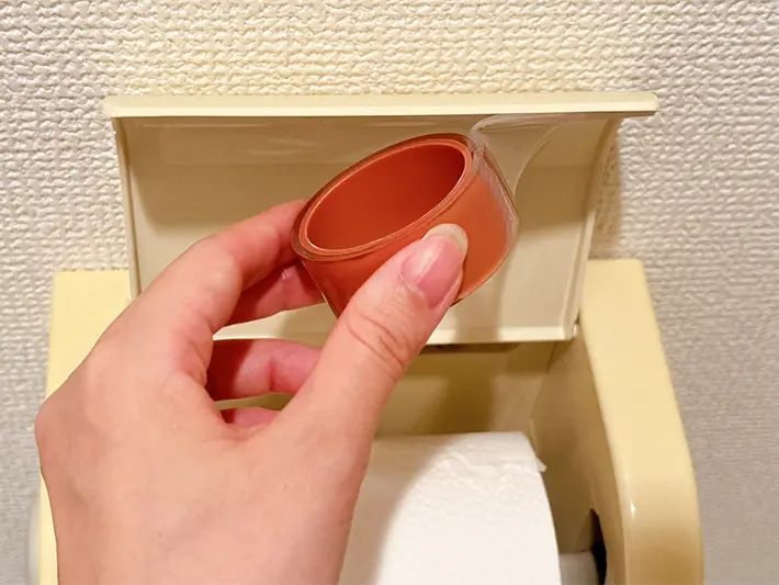 トイレットペーパーホルダーの蓋にゲルテープを貼る写真（撮影：grapeライフハック編集部）