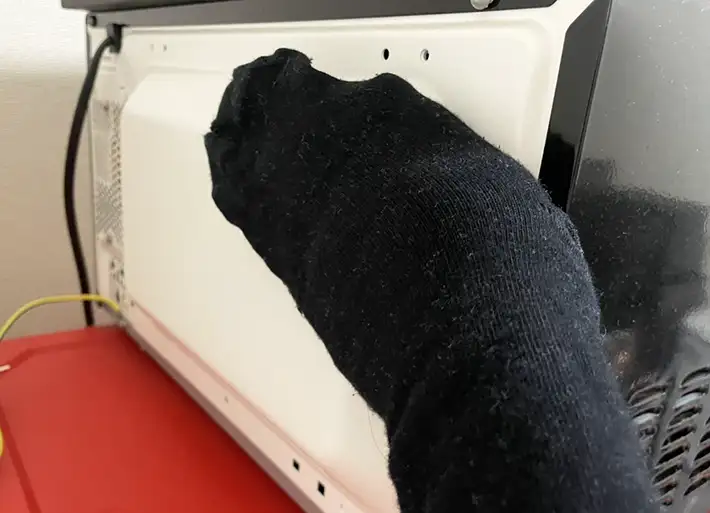 電子レンジ裏をなでる写真（撮影：grapeライフハック編集部）
