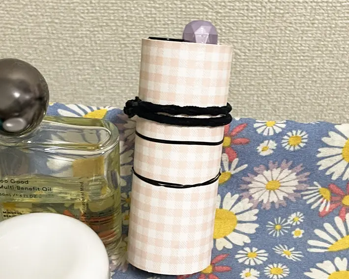 折り紙を貼りつけたトイレットペーパーにヘアゴムを巻きつける写真（撮影：grapeライフハック編集部）