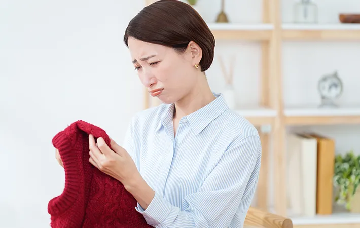 汚れた服を見る女性の写真
