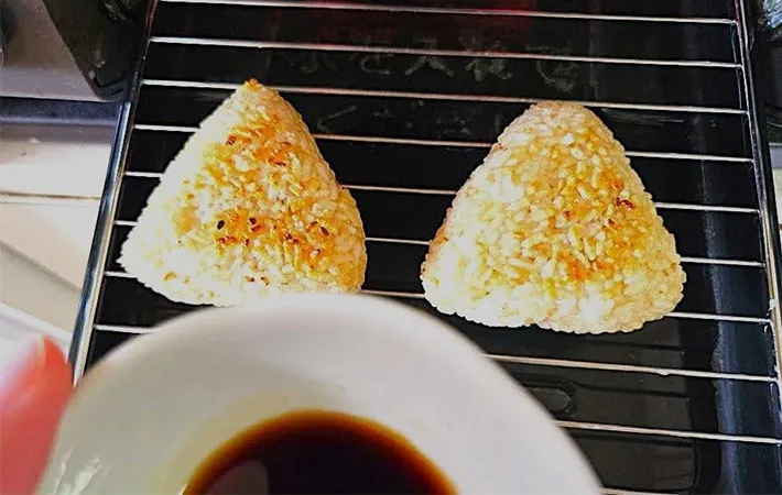 おにぎりに仕上げのタレを塗るところの画像（撮影：キジカク）