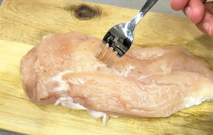 鶏むね肉にフォークで穴を開けている画像（撮影：キジカク）