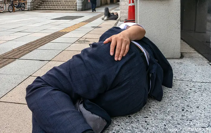 酔って道路で寝る人の写真