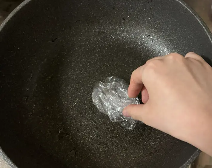 ラップでフライパンの油汚れを拭き取る写真（撮影：grapeライフハック編集部）