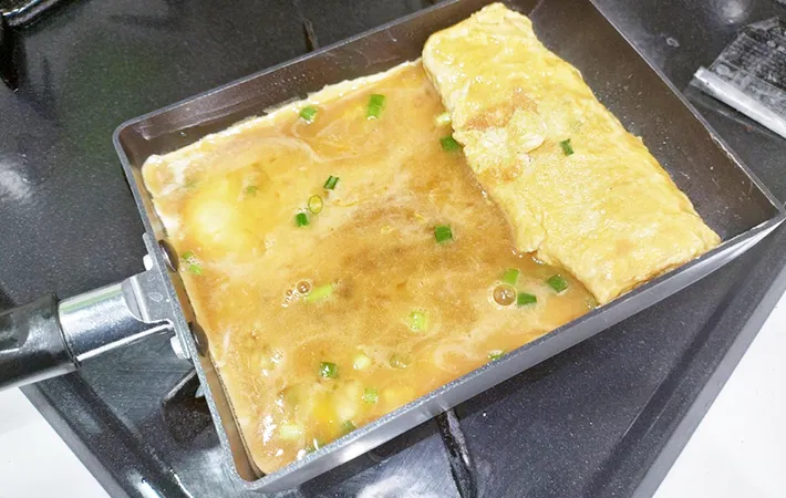 玉子焼きを巻いている画像（撮影：エニママ）