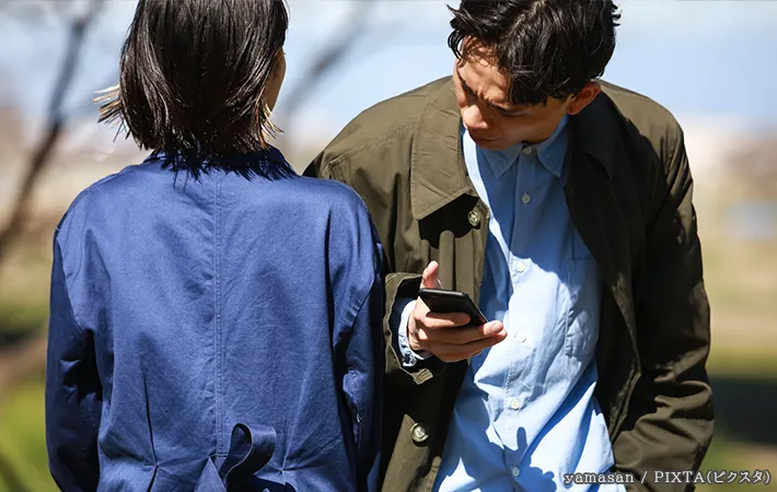 スマホを持った人がぶつかる写真