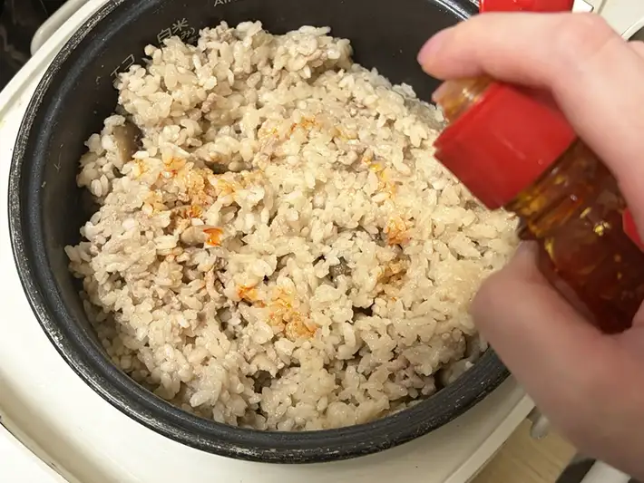 炊き上がったご飯にラー油をかける写真（撮影：grapeフード編集部）