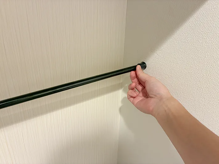 トイレの壁の間につっぱり棒を設置する場面（撮影：grapeライフハック編集部）