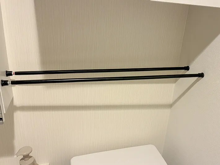 トイレの壁の間に設置した2本のつっぱり棒（撮影：grapeライフハック編集部）