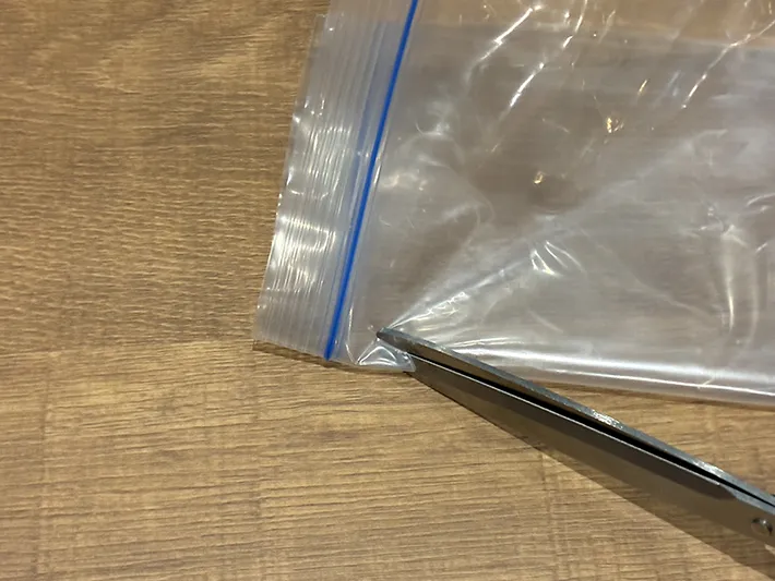ジッパー袋のジッパー下をハサミで切り取る場面（撮影：grapeライフハック編集部）