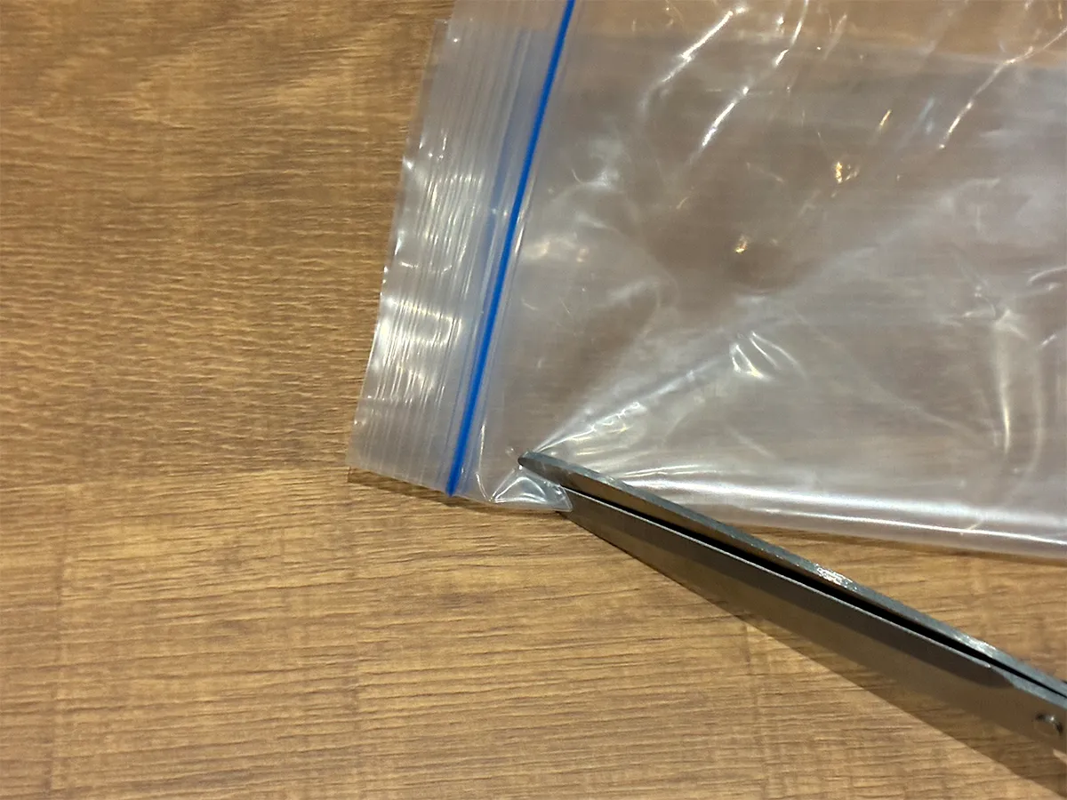 ジッパー袋のジッパー下をハサミで切り取る場面(撮影:grapeライフハック編集部)