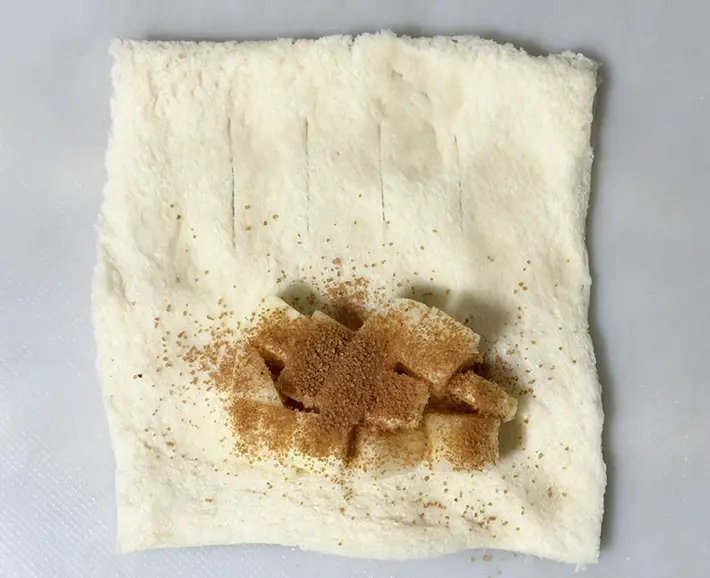 食パンにリンゴをのせてシナモンシュガーをかける写真（撮影：grapeフード編集部）