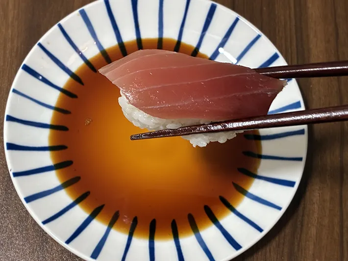 箸でつかんだマグロの寿司（撮影：grapeフード編集部）