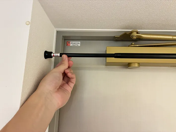玄関のドア上につっぱり棒を設置する場面（撮影：grapeライフハック編集部）