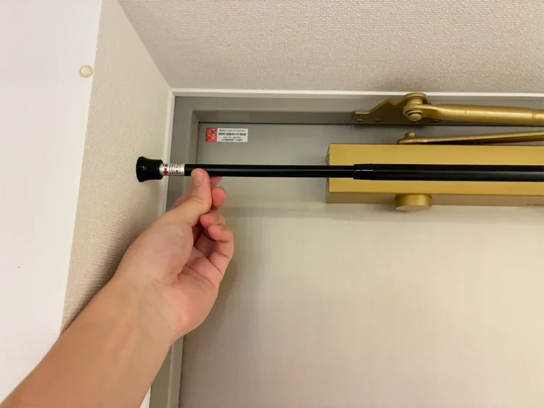 玄関のドア上につっぱり棒を設置する場面(撮影:grapeライフハック編集部)