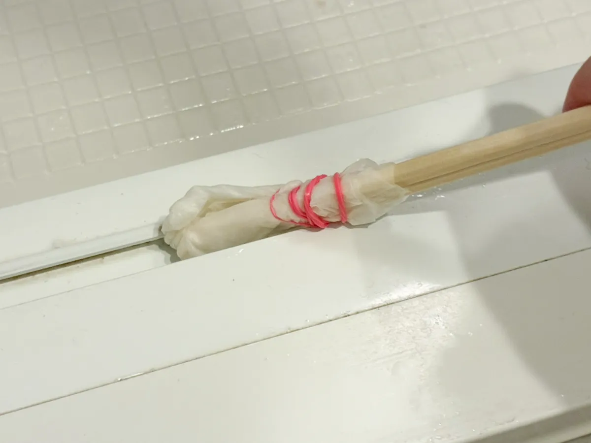 キッチンペーパーを巻いた割り箸でレールを掃除する場面（撮影：grapeライフハック編集部）