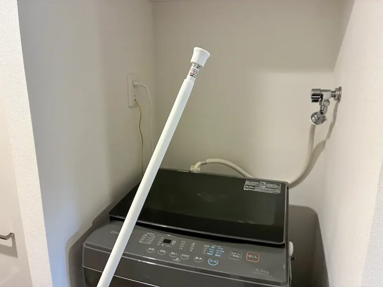 洗濯機そばで手にするつっぱり棒(撮影:grapeライフハック編集部)