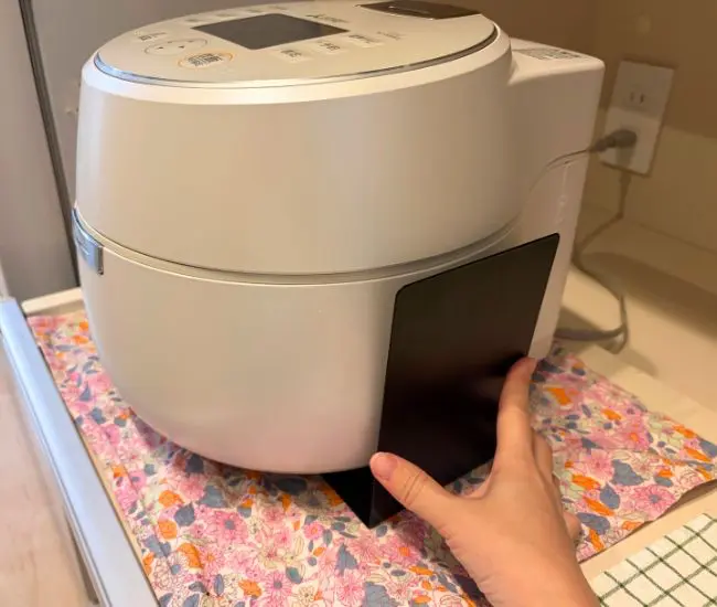 炊飯器の下にブックエンドを差し込んだ様子（撮影：grapeライフハック編集部）