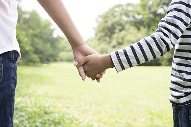 Holding Hands siblings in the grass